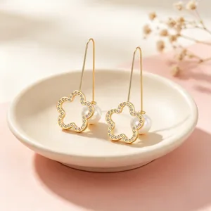 Detailansicht der eleganten hohlen Blumenohrringe mit Strass und weißen Perlen.