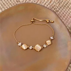 Close-up of golden adjustable bracelet with square cat's eye stones and zircons