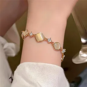 Elegant cat-eye stone bracelet with sparkling zircons shown on a wrist, gold finish detail.