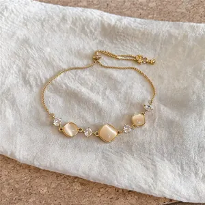 Close-up of elegant gold adjustable bracelet with square cat-eye stones and sparkling zircons