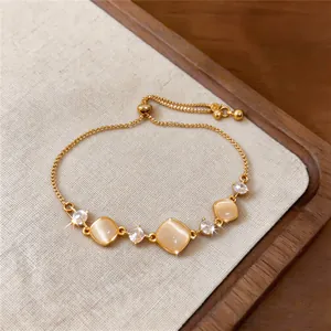 Detailed macro view of an adjustable gold bracelet with square cat-eye stones and zircons.