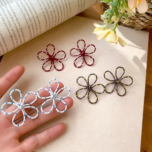 Polka dot hollow flower stud earrings in multiple colors held by hand