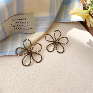 Macro view of brown hollow flower stud earrings with vibrant yellow polka dots on petals