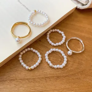 Détail rapproché montrant des bagues en perles délicates et des bagues ouvertes dorées