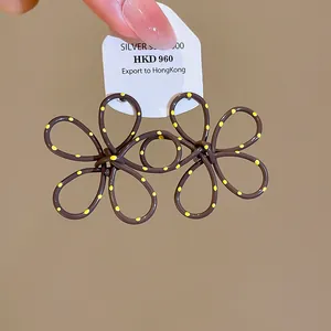 Close-up of spray-painted brown floral stud earrings with vibrant yellow polka dots