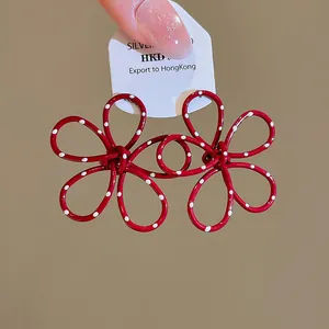 Close-up macro view of vibrant red lacquer flower earrings with cute white polka dots