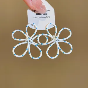 Close-up of white flower cutout earrings with blue polka dots and S925 silver needles