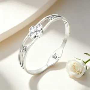 Detail of a silver stainless steel bangle with crystal four-leaf clover design and spring clasp