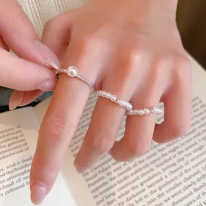 Gros plan d'un ensemble de bagues en perles plaquées or 14 carats sur une main
