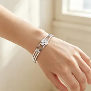 Close-up detail of silver-toned stainless steel clover bangle with crystals on wrist.