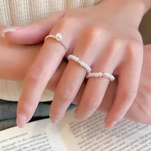 Vue détaillée d'un ensemble de bagues en perles plaqué or 14 carats porté sur les doigts