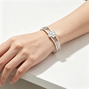Macro view of a stainless steel lucky clover bracelet with clear stones on a wrist