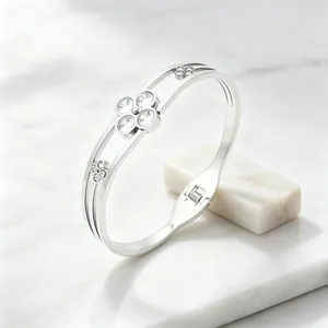 Close-up view of elegant silver clover bangle featuring sparkling gemstones and spring clasp.