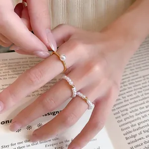 Vue détaillée d'un ensemble de bagues en perles plaquées or 14 carats sur un doigt