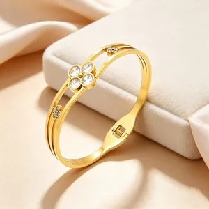 Detailed view of a gold stainless steel clover bangle with sparkling clear stones.