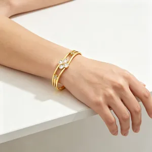 Detail view of gold stainless steel lucky clover bracelet with crystals on female wrist
