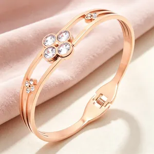 Detailed close-up of rose gold four-leaf clover bangle bracelet with clear crystals