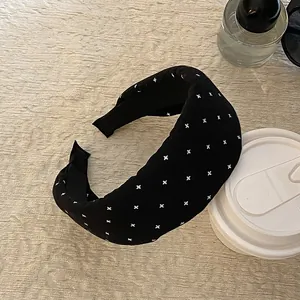 Nahaufnahme des schwarzen Stoffstirnbands mit weißem Kreuzmuster und breitem Design.