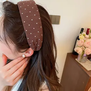 Detailansicht eines braunen Stoff-Haarreifens mit weißem Kreuzmuster an einem Model