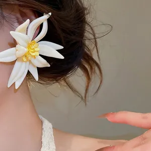 Elegantes pendientes de flores blancas con centro de cristal amarillo en el modelo