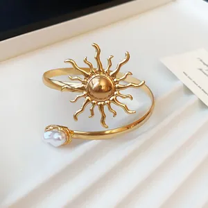 Makro-Detail von Vintage-Armreif mit Sonnenmotiv und eleganter Barockperle als Ornament.