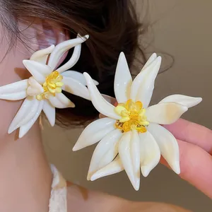 Primo piano dettagliato di orecchini a lobo a fiore bianco con centri in cristallo giallo