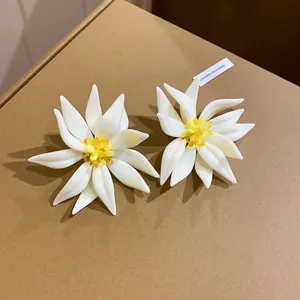 Primo piano di orecchini a fiore bianchi con centri in cristallo giallo brillante