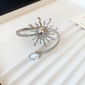 Detailansicht eines silbernen Metall-Armreifs mit Sonne und Perle auf einem Tablett