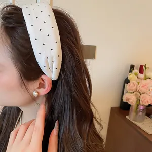 Detail eines weißen Stoff-Stirnbands mit schwarzen Sternenmustern im Haar.