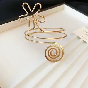 Detaillierte Nahaufnahme eines goldenen Metall-Armreifs mit Blumen- und Spiral-Design