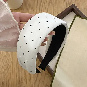 Detailansicht eines gepolsterten weißen Stoffstirnbands mit minimalistischem schwarzem Kreuzmuster