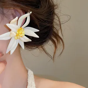 Dettaglio ravvicinato di orecchini a lobo a forma di fiore bianco e cristallo giallo