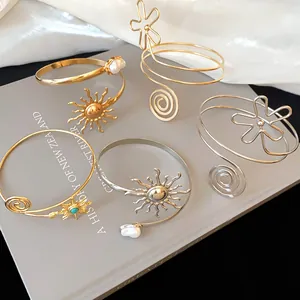 Detail von Vintage-Metall-Armreifen mit Sonnen- und Blumenmotiven in Gold und Silber.
