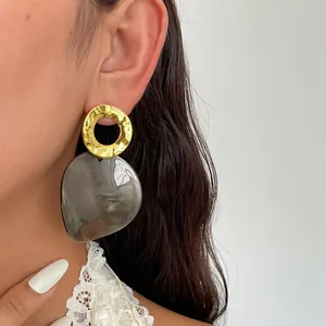 Vue détaillée de boucles d'oreilles rétro avec anneau en métal doré et pendentif acétate gris