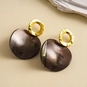 Gros plan sur les boucles d'oreilles vintage avec anneaux d'or et plaques irisées.
