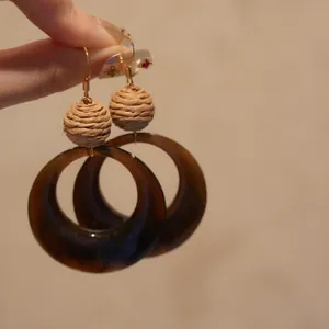 Vue détaillée de boucles d'oreilles ethniques en raphia et résine avec crochets dorés