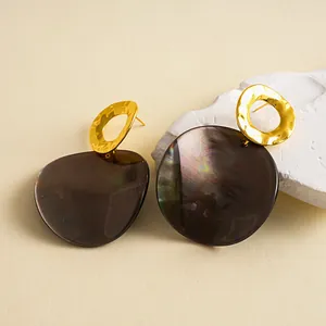 Gros plan de boucles d'oreilles pendantes géométriques dorées et acétate irisées