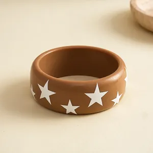 Close-up van een bruine hars armband met witte sterpatronen op een beige achtergrond