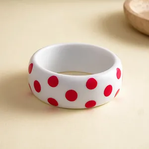 Detailopname van witte harsarmband met rode stippen voor een retro modieuze look