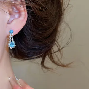 Detaillierte Nahaufnahme eines funkelnden blauen Tropfenohrrings an einem Modelohr