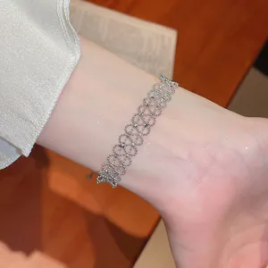 Detailansicht eines silbernen Armbands mit filigranem, hohlem Spitzenmuster am Handgelenk