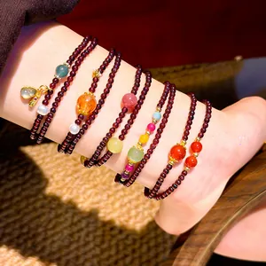 Dettaglio macro di braccialetti multifilo in granato e pietre dure sul polso
