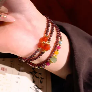 Elegante bracciale di perle di granato in stile cinese con ciondoli in pietra colorata.