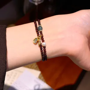Primo piano di un braccialetto di granato a due fili in stile New Chinese con ciondolo dorato