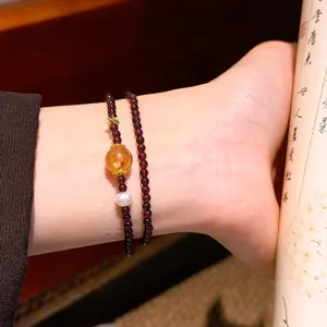 Dettaglio ravvicinato di bracciale in granato vintage con ambra e perla bianca pura