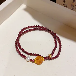 Vista dettagliata del bracciale in granato a due fili con perla d'ambra e accento di perla