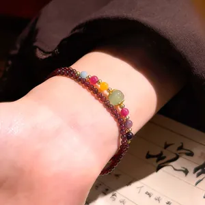 Primo piano di un braccialetto di granato a due strati con pietre di giada colorate al polso