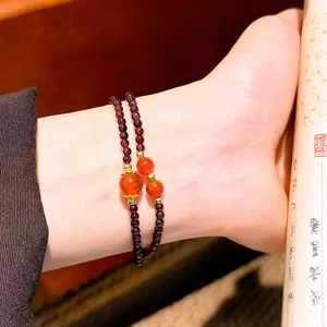 Elegante bracciale a due fili in granato e corniola sul polso di una donna con luce calda