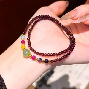 Dettaglio di un bracciale di granato a doppio giro con pietre preziose colorate.