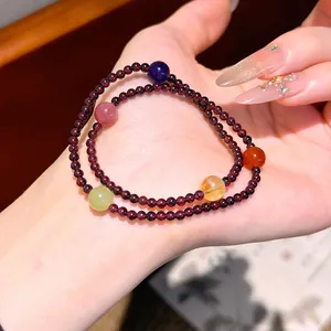 Primo piano di un braccialetto di perle di granato a due fili con pietre colorate